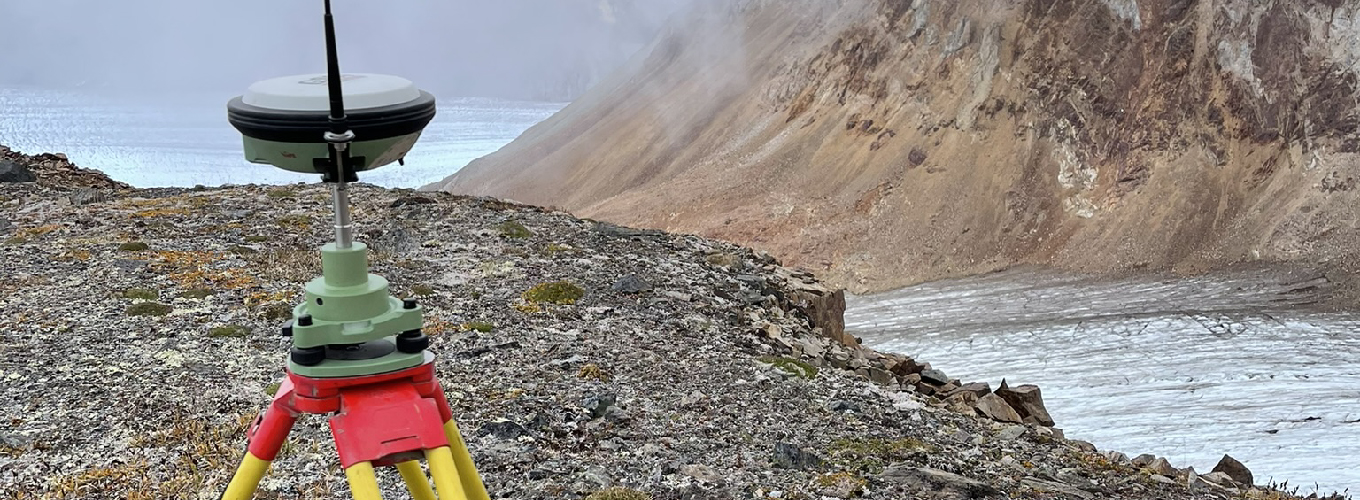 Surveyors with their equipment set up near a majestic glacier close to Atlin, British Columbia, capturing the juxtaposition of man-made tools against the vast, ancient ice and rugged surrounding landscape